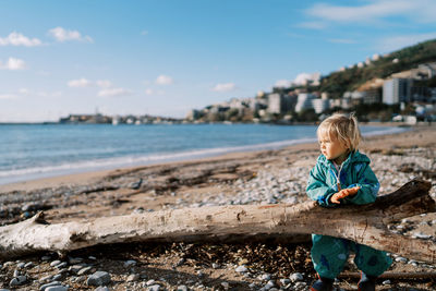 Rear view of boy standing on beach against sky