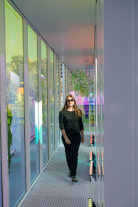 Full length portrait of woman standing against glass