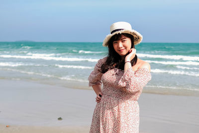 Young woman wearing hat while standing on beach