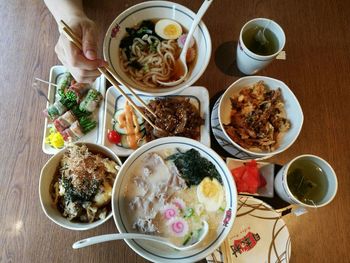 Directly above shot of cropped hands holding chopsticks over food