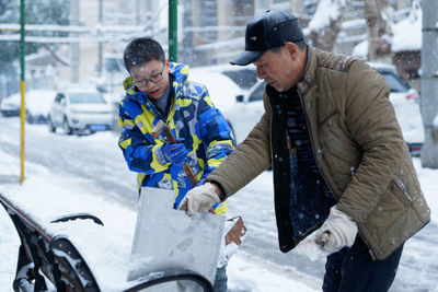 People making snowman on bench during winter