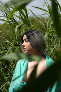 Young woman looking away while sitting amidst grass