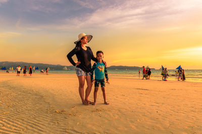 People on beach against sky during sunset