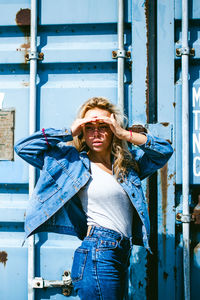 Young woman wearing denim jacket against metal structure