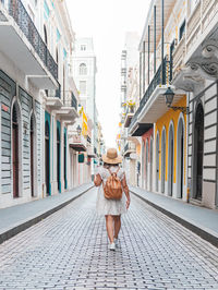 Young woman walking with white dress through a city hall of buildings from puerto rico san juan