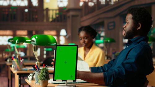 Side view of man using mobile phone while sitting on table