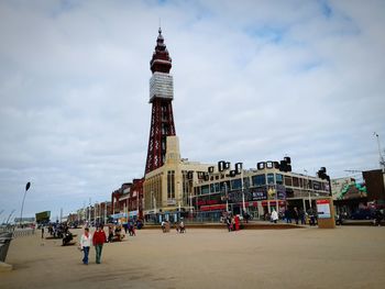 People on beach in city against sky