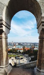 Arch bridge over river amidst buildings against sky