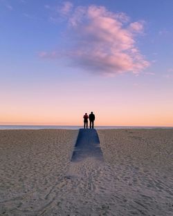 People on beach against sky during sunset