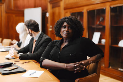 Portrait of confident businesswoman with hands clasped sitting in board room during meeting