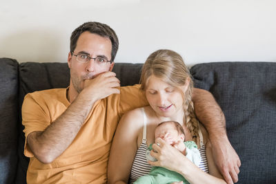 Portrait of man sitting with woman and baby boy on sofa at home