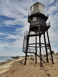 Low angle view of lighthouse tower on beach against sky