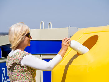 Midsection of woman holding yellow umbrella against sky
