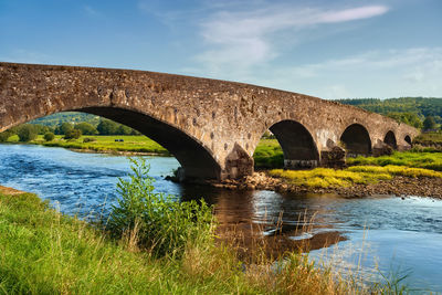 Arch bridge over river against sky