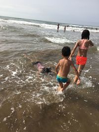 Rear view of shirtless boy enjoying at beach