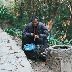 Man sitting on rock against trees