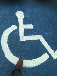 Low section of man by wheelchair access sign on road