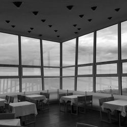 Empty chairs and tables in restaurant against sky