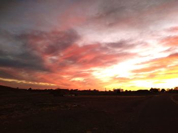 Scenic view of dramatic sky over land during sunset