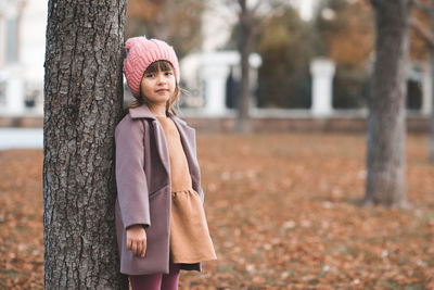 Happy smiling child 4-5 year old wear jacket and hat in park with fall leaves over nature background