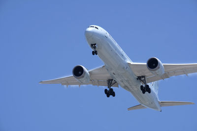 Low angle view of airplane flying against clear blue sky