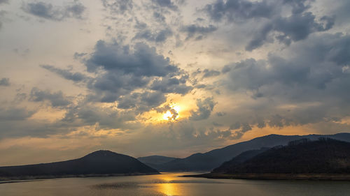 Stunning view of a lake among hills and mountains with sun reflection