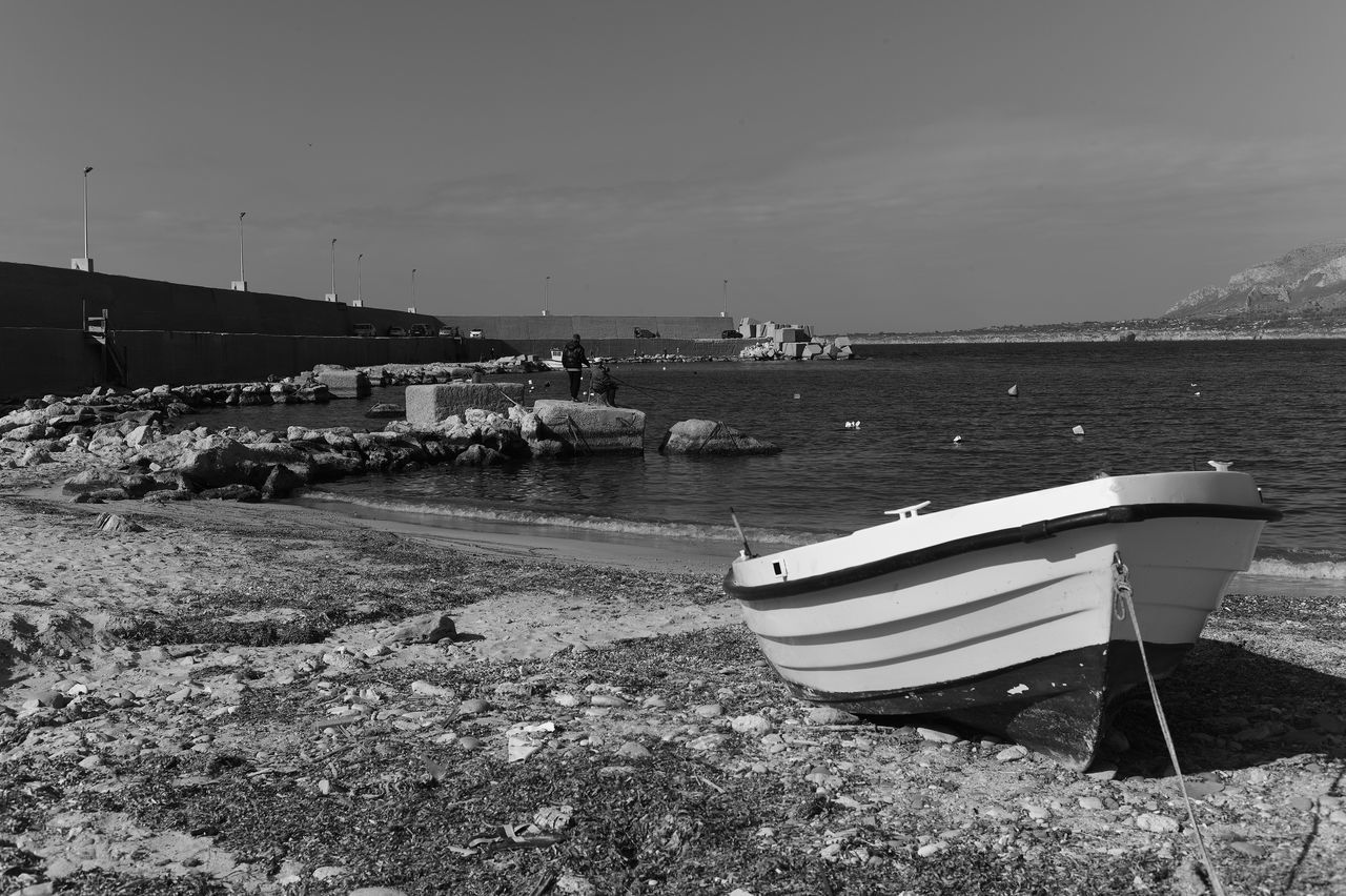 water, nautical vessel, black and white, beach, sea, sky, nature, transportation, land, moored, monochrome, mode of transportation, monochrome photography, coast, vehicle, shore, boat, no people, day, tranquility, scenics - nature, ship, tranquil scene, watercraft, beauty in nature, outdoors, architecture, environment, non-urban scene, travel, sand, pier, harbor, travel destinations, coastline