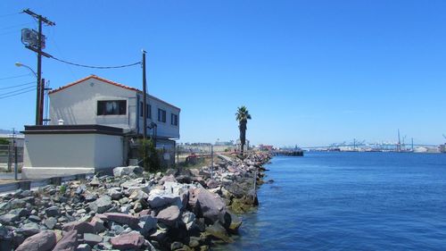 Abandoned house by sea against clear blue sky