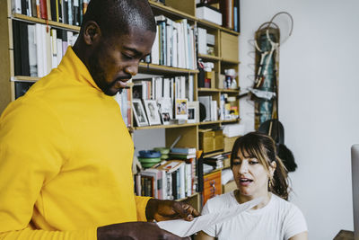 Mid adult woman talking with boyfriend reading receipt at home