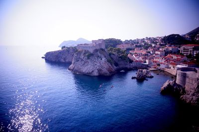 Buildings by sea against clear sky