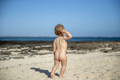 Rear view of shirtless boy on beach