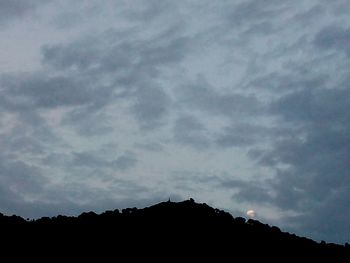 Silhouette landscape against cloudy sky