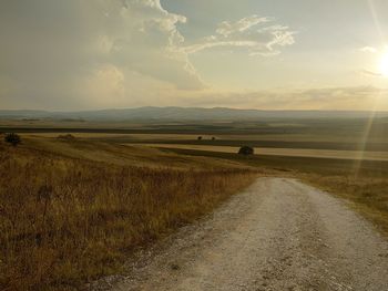 Road amidst field against sky