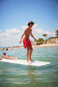 Two happy teenage boy having fun on swim board in the sea