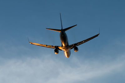 Low angle view of airplane flying against blue sky