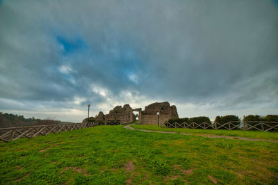 Old ruin on field against cloudy sky