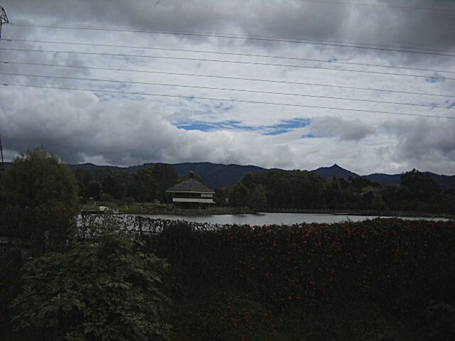 mountain, sky, water, mountain range, tranquil scene, cloud - sky, scenics, tranquility, beauty in nature, lake, landscape, nature, built structure, cloudy, cloud, river, architecture, house, idyllic, building exterior