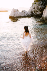 Rear view of woman on rock at sea shore