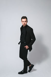 Portrait of young man standing against white background