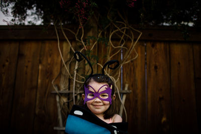 Young girl in dress up standing in front of vines