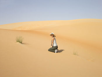 Person on sand dune in desert against sky