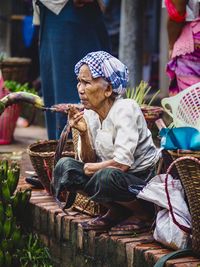 Woman sitting in basket for sale at market stall