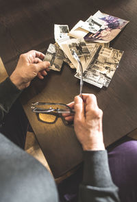 Hands of senior woman holding old photography and spectacles