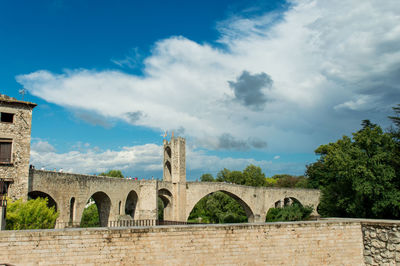 Arch bridge against cloudy sky