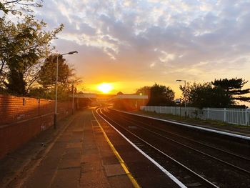 Railroad tracks against sky during sunset