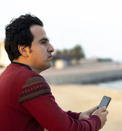 Side view of young man using mobile phone
