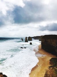 Scenic view of beach against cloudy sky