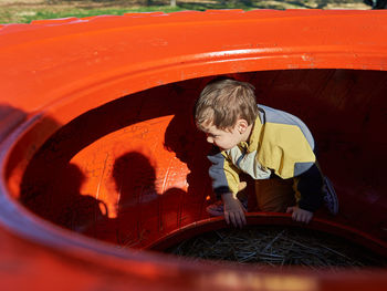 Cute boy playing inside and over a colorful tractor wheel at the farm fair on halloween