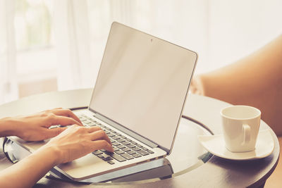 Midsection of man using laptop on table