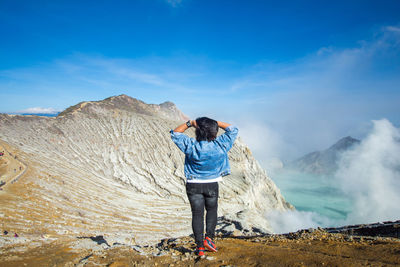 Rear view of man standing on land against sky